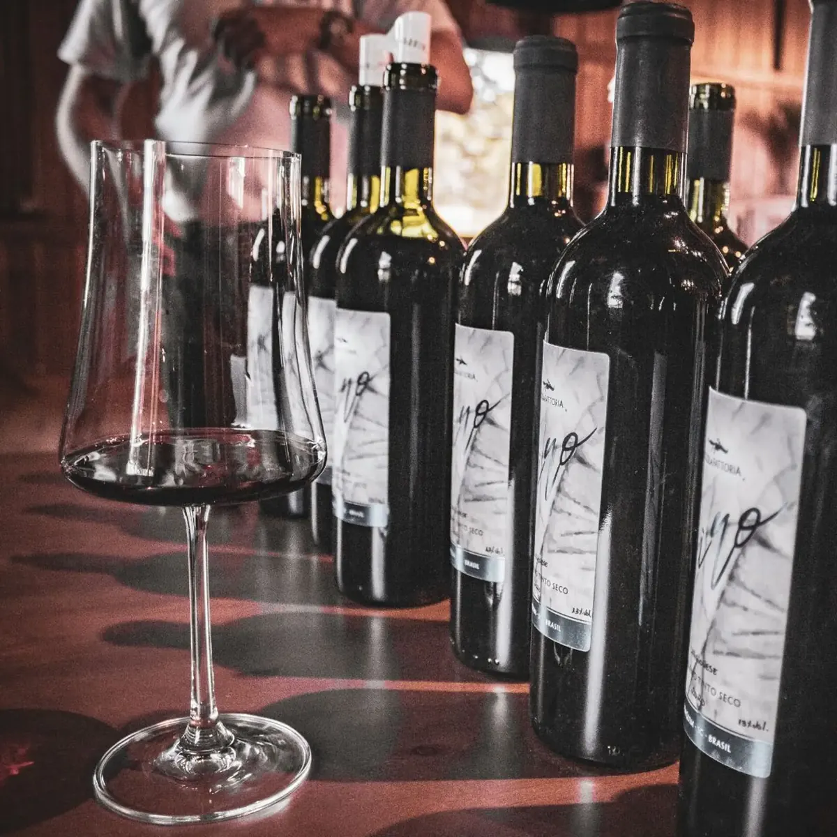 Garrafas de vinho e taça sobre o balcão da adega