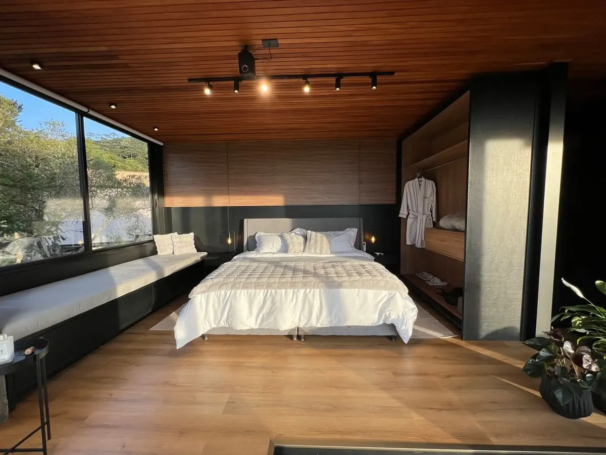 Quarto da cabana com cama king size e janela para as araucárias