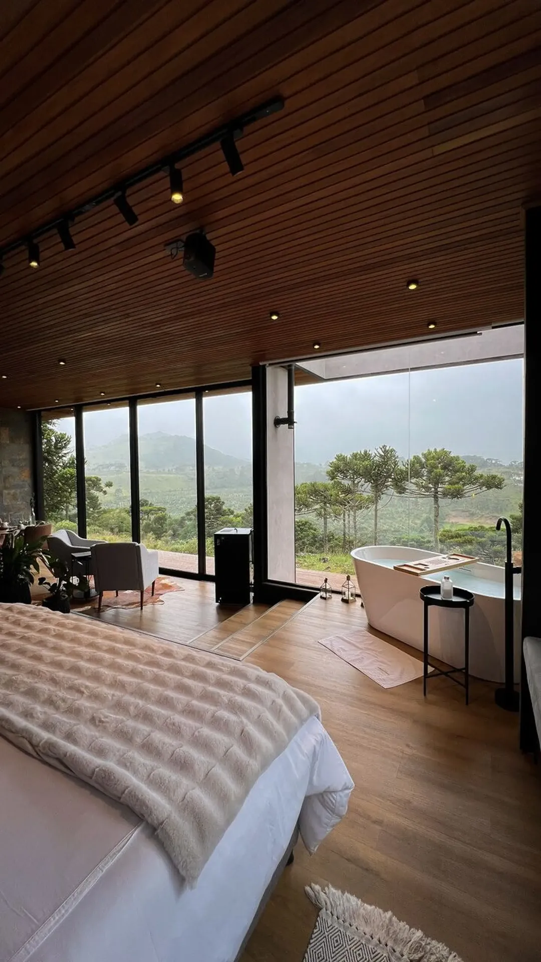 Quarto da cabana com cama king size e parede de vidro para a serra